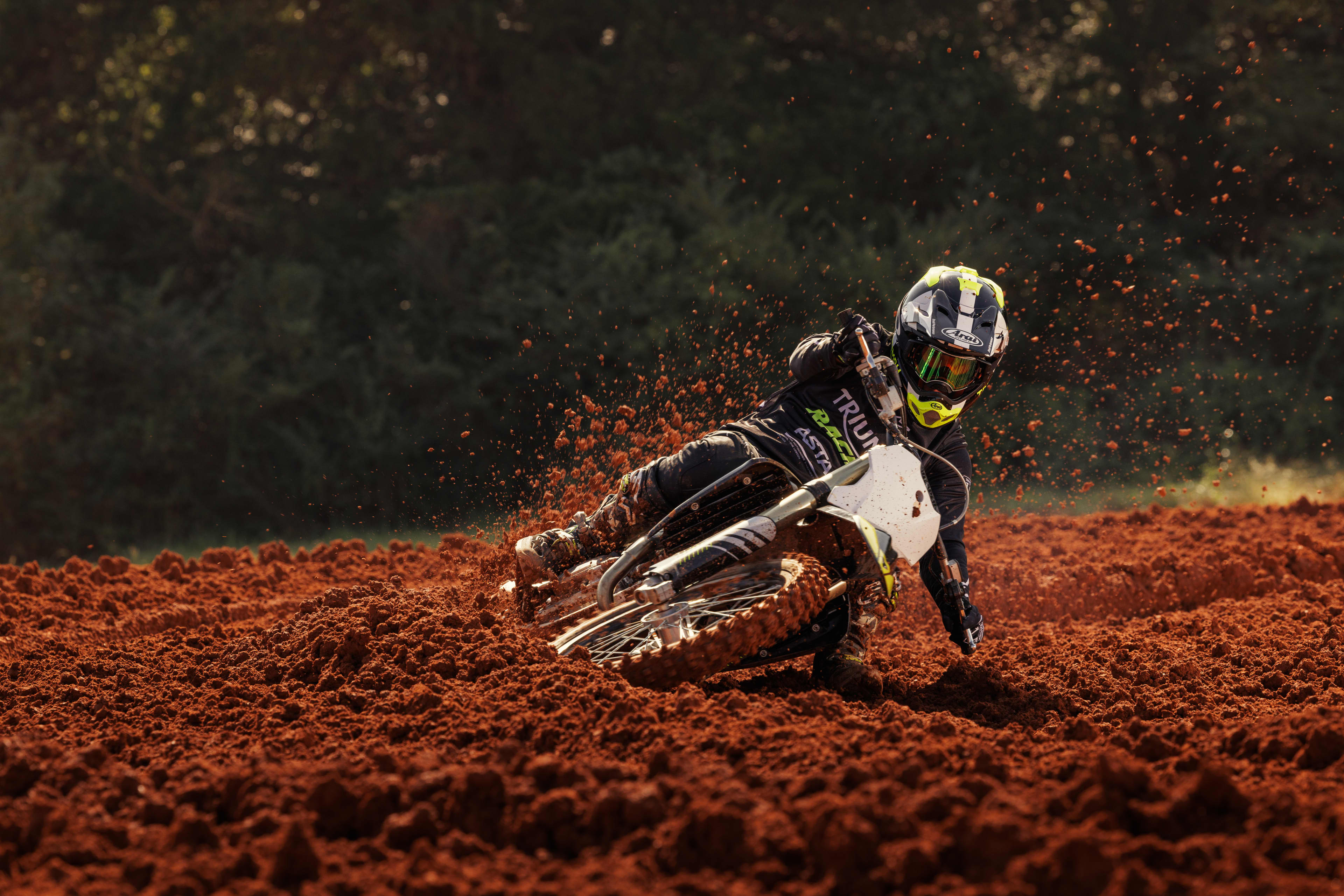Rider on a Triumph TF 250-X (MY24) leaning in the red mud